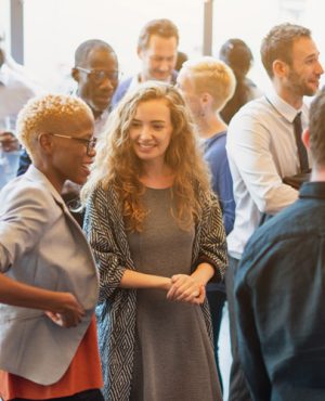 Diverse group of people socializing at a casual gathering. Men and women of various ethnicities engaged in conversation, enjoying a lively social event. Diverse people mingle at a social event.